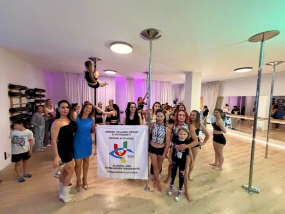 Ein Gruppenfoto der Teilnehmerinnen und Organisatorinnen der Veranstaltung, die sich rund um das Banner der Italienischen Union der Blinden und Sehbehinderten – Sektion Südtirol versammelt haben – als Zeichen des solidarischen Zwecks der Initiative